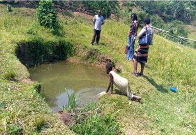 A child collects water from a dirty pit